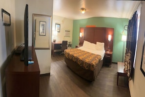 A hotel room with a bed, a desk, a television, and a chair.