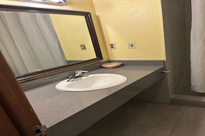 Ein Badezimmer mit Waschbecken, Spiegel und Duschvorhang.