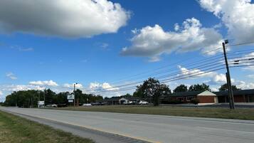 A road with a building in the background, a clear sky, and power lines.
