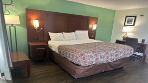 Habitación de hotel con una cama grande, dos mesitas de noche, un escritorio con silla y una lámpara.