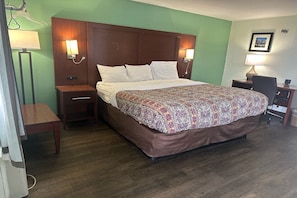 Habitación de hotel con una cama grande, dos mesitas de noche, un escritorio con silla y una lámpara.