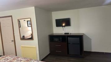 Une chambre d’hôtel comprenant un lit, une commode avec un téléviseur, un four à micro-ondes et un réfrigérateur.