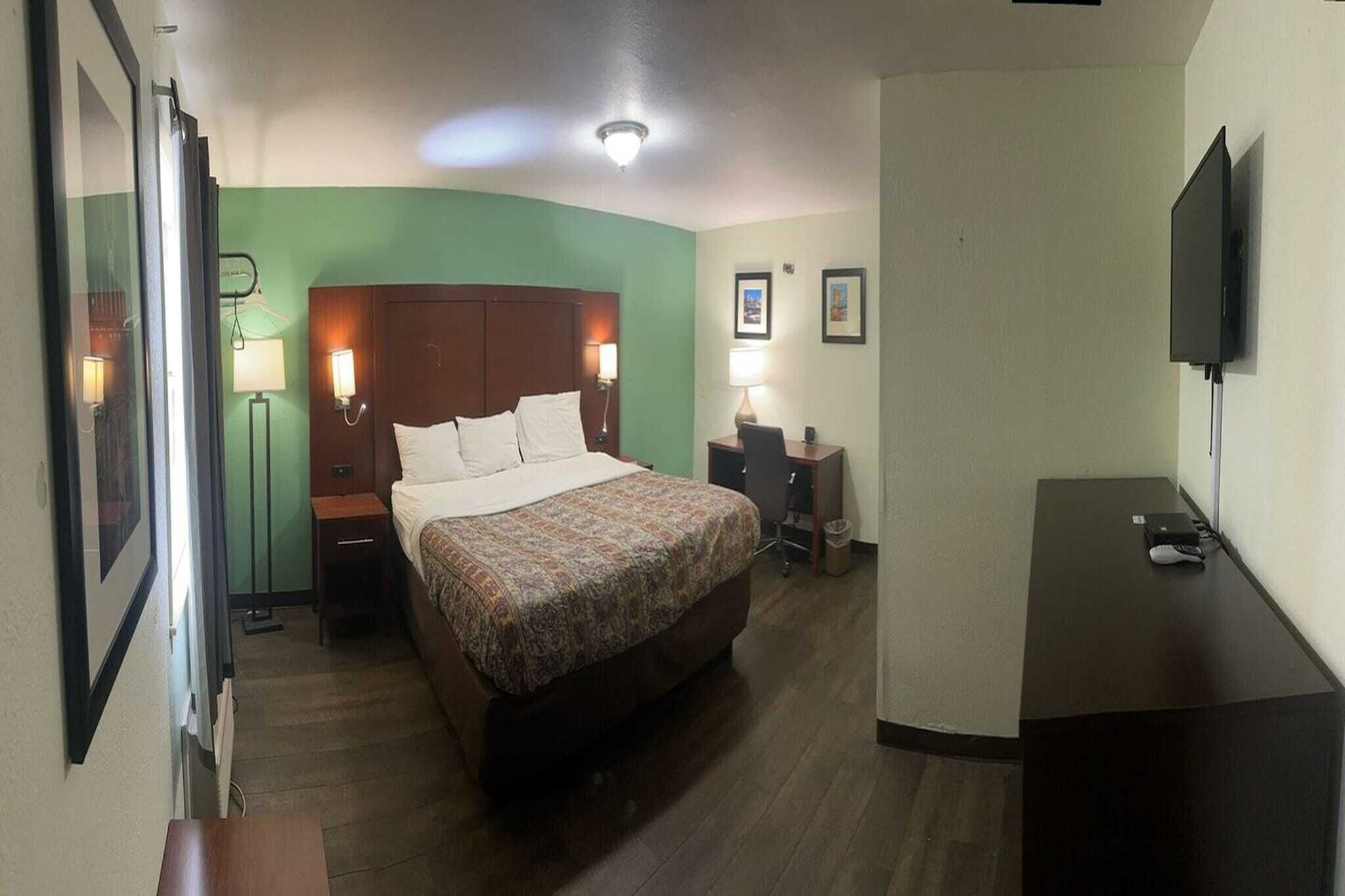 Une chambre d’hôtel comprenant un lit, des tables de chevet, un bureau, une télévision et un miroir.