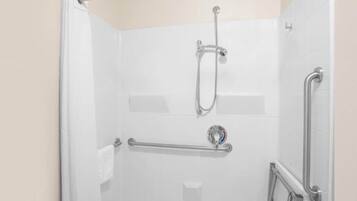 A shower with a grab bar, a handheld showerhead, and a wall-mounted faucet.