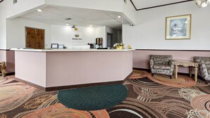 Un comptoir d’accueil avec une enseigne « Relax Inn », un tableau encadré accroché au mur et une moquette à motifs.