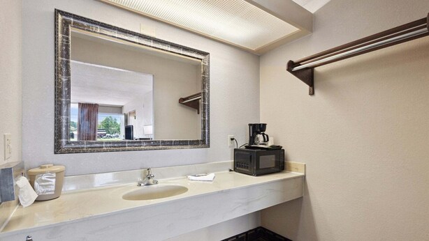 Une salle de bain équipée d’un grand miroir, d’un lavabo, d’un distributeur de serviettes et d’une machine à café.