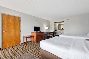 Una habitación de hotel con cama, escritorio, televisor, cómoda y espejo.