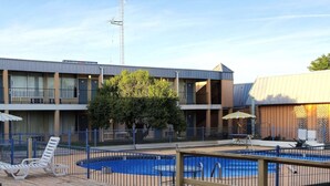 Et hotel med swimmingpool, en indhegnet terrasse og en bygning med flere altaner.