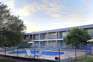 Un hôtel doté d’une piscine, d’une terrasse clôturée et d’un immeuble à plusieurs étages avec des balcons.