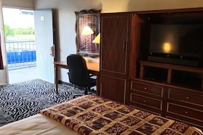 Una habitación de hotel con una cama, un escritorio, una silla, un televisor y un armario.