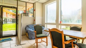 A room with a wooden table and chairs, a covered couch, a sliding glass door leading outside, and a small window. - 2 Full Beds|Non-Smoking (Livingston)