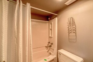 A bathroom with a shower, toilet, and towel rack.