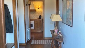 A hallway leading to a kitchen with wooden beams, a radiator, a table with a lamp, and a framed picture on the wall. - Semi-detached house in Vilar dúrtx (Soriguerola)