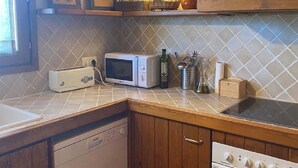 A kitchen with wooden cabinets, a microwave, a toaster, and a stove. - Semi-detached house in Vilar dúrtx (Soriguerola)
