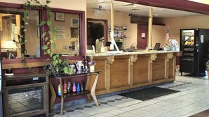 Un espace d’accueil comprenant un comptoir en bois, une vitrine et un distributeur automatique.