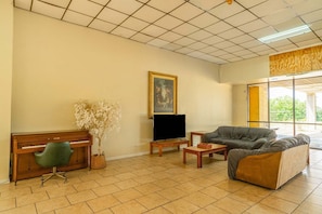 Una sala de estar con un piano, una televisión, un sofá, una mesa de centro y un cuadro en la pared.