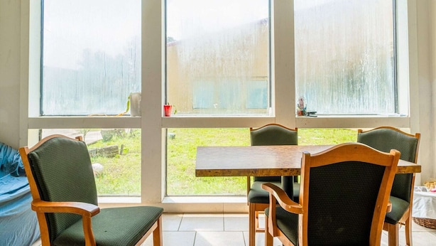 Ein Zimmer mit einem großen Fenster, einem Holztisch und vier Stühlen.