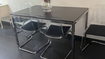 A conference table with four chairs, a vase with red flowers, and a clear plastic chair.