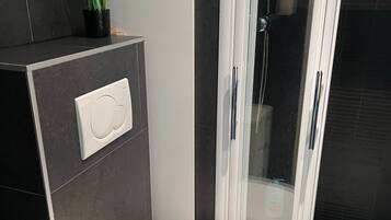 Ein modernes Badezimmer mit Toilette, Duschkabine und einer wandmontierten Bedienkonsole.