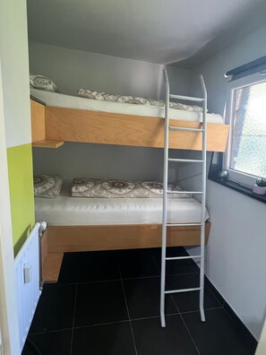 A bunk bed room with a ladder, a window, and a radiator.