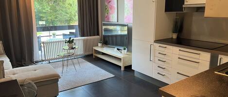 A modern kitchen with a built-in oven, a dining area with a table and chairs, and a large window with curtains.