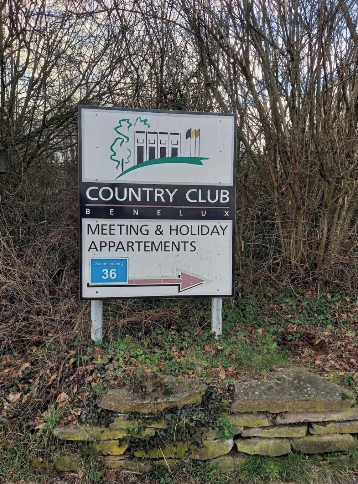 A sign for Country Club Benelux, indicating Meeting & Holiday Apartments with a directional arrow.