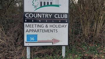 A sign for Country Club Benelux, indicating Meeting & Holiday Apartments with a directional arrow.