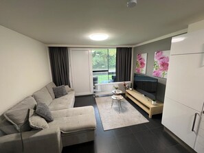 A modern living room with a sofa, a coffee table, a TV, and a radiator.