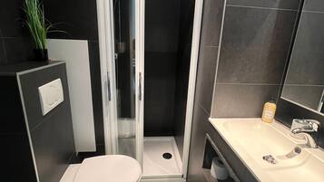 Een moderne badkamer met een douchecabine, toilet en ligbad.