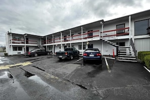 A multi-story motel with a parking lot, a staircase, and a visible entrance.