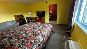 Een hotelkamer met een bed, een televisie, een bureau en een raam.