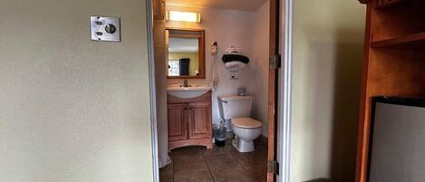Et badeværelse med vask, spejl, toilet og håndklædestang.