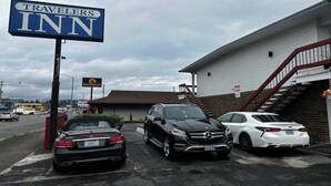 A Travelers Inn sign, a parking lot with three cars, and a building with a staircase.