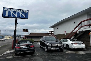 A Travelers Inn sign, a parking lot with three cars, and a building with a staircase.