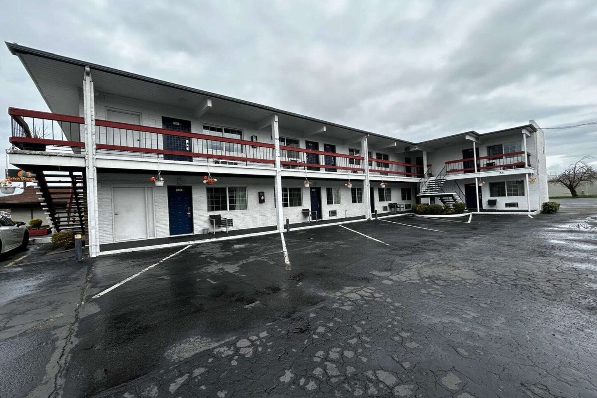 Een motel met meerdere verdiepingen, een centrale trap, een overdekte parkeerplaats en een plat dak.