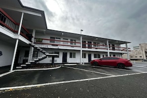 A multi-story building with a red car parked in the parking lot.