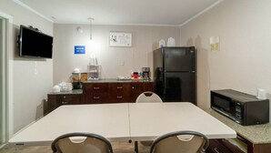 A small kitchenette with a microwave, refrigerator, and coffee maker. There is a dining table with chairs and a TV mounted on the wall. - Queen Bed|Non-Smoking (Lamesa TX)