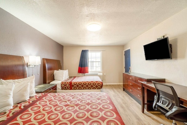 A hotel room with two beds, a desk, a chair, a TV, and a window with curtains.