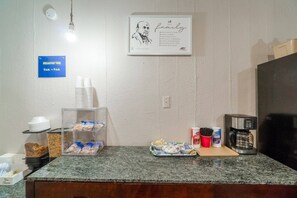 A breakfast area with a sign indicating breakfast time, a coffee machine, and various food items on the counter. - 2 Full Beds|Non-Smoking (Lamesa TX)