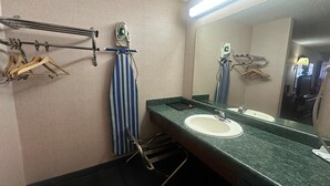 Ein Badezimmer mit Waschbecken, Spiegel, Handtuchhalter und Bügeleisen.