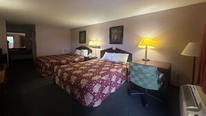 Habitación de hotel con dos camas, un escritorio, una silla, una lámpara y un calentador.