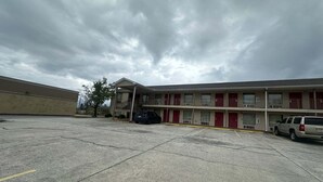 Ein Motel mit Parkplatz, ein mehrstöckiges Gebäude und ein Baum.