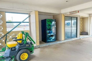 Entrada de un edificio con una carretilla elevadora, una máquina expendedora y un letrero que anuncia bebidas y hielo.