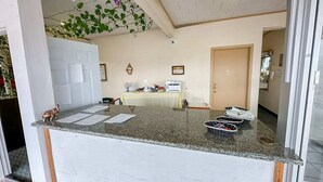 A reception area with a counter, a table with a printer, and a door leading to another room.