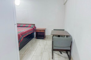Una habitación pequeña con cama, mesita de noche, mesa y silla.