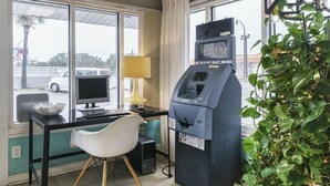 Une pièce équipée d’un bureau, d’un ordinateur, d’un distributeur automatique de billets et d’une plante.
