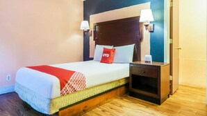 Une chambre d’hôtel avec un lit, des lampes de chevet, une table de nuit et une porte.