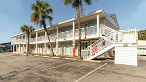 Un motel doté de nombreuses chambres, d’un escalier et de palmiers.
