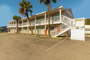 A motel with multiple balconies, a staircase, and a parking lot.