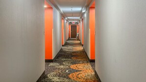 Een hotelgang met een vloerbedekking, oranje wanden en een deur aan het einde.